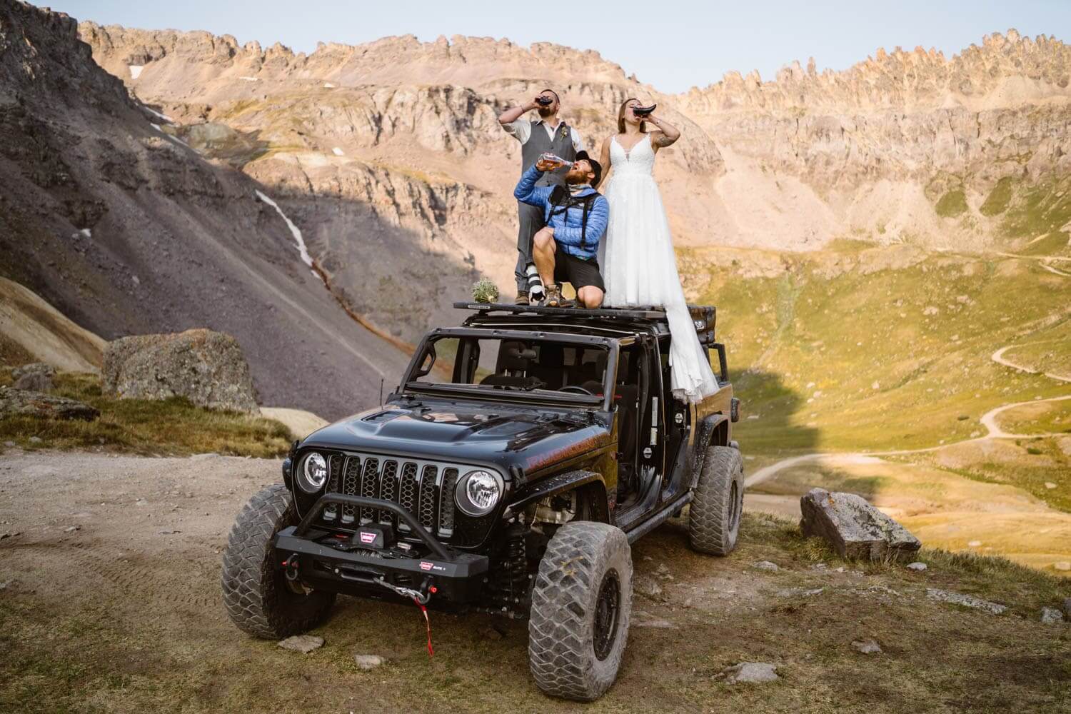 Couple sharing drinks with Sean from vows and peaks on their Jeep.