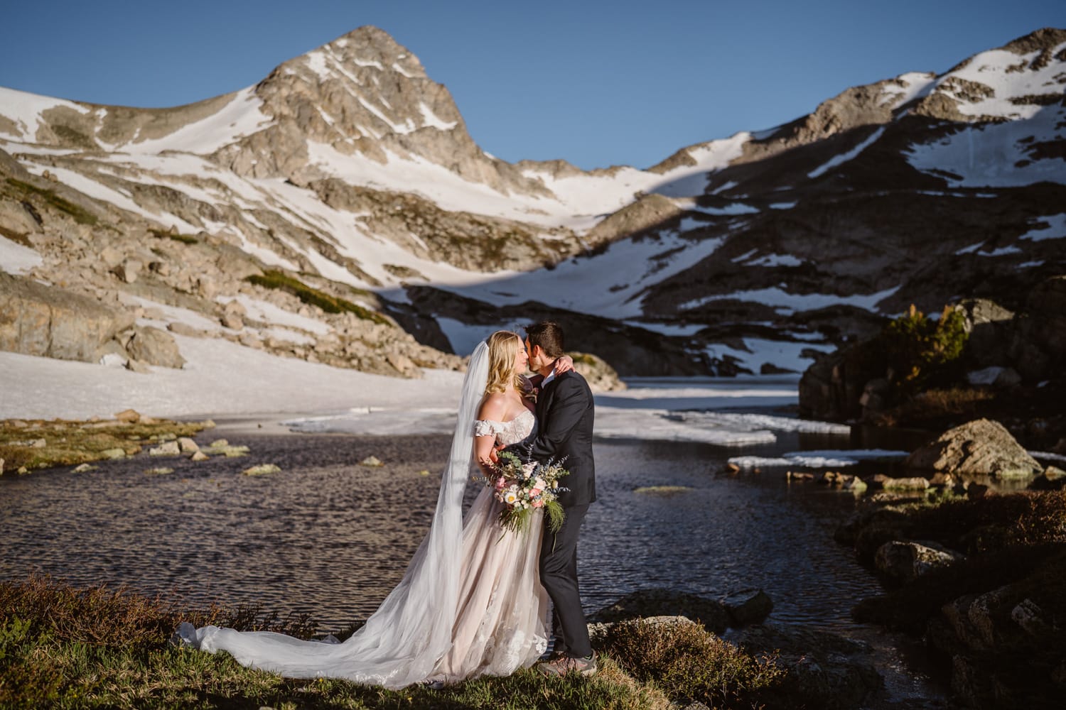 Couple hugging near an alpine lake at sunrise for their elopement.