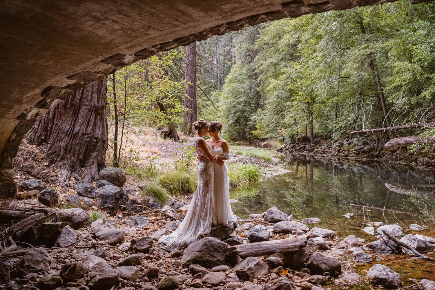 Bride and bride under the bridge near the water for their elopement in Yosemite.