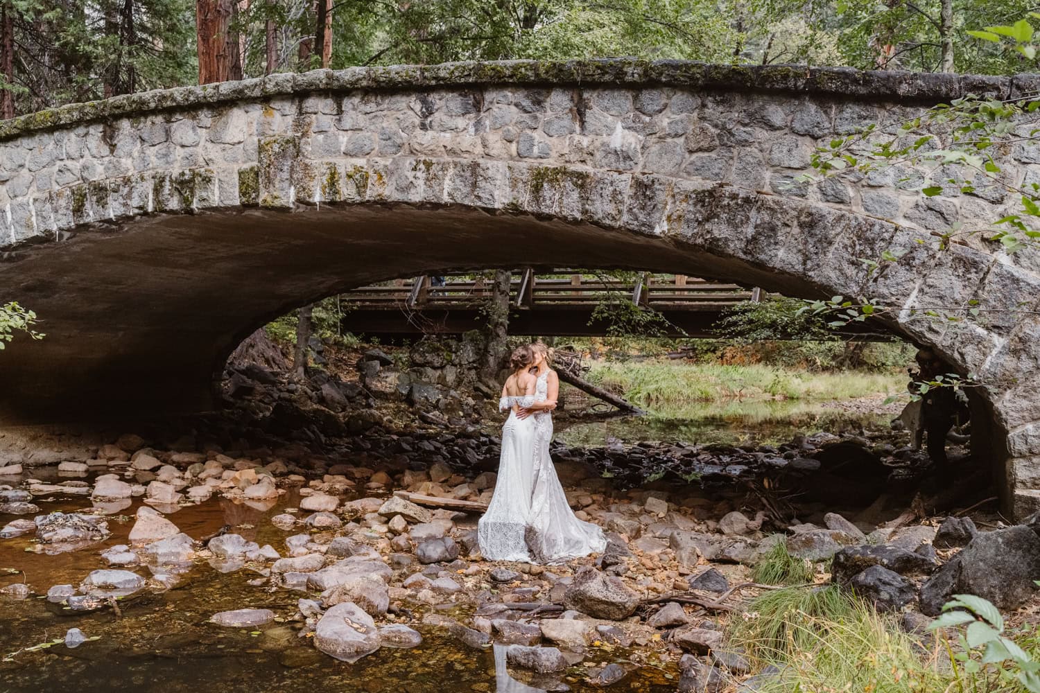 Bride and bride under the bridge near the water for their elopement in Yosemite.