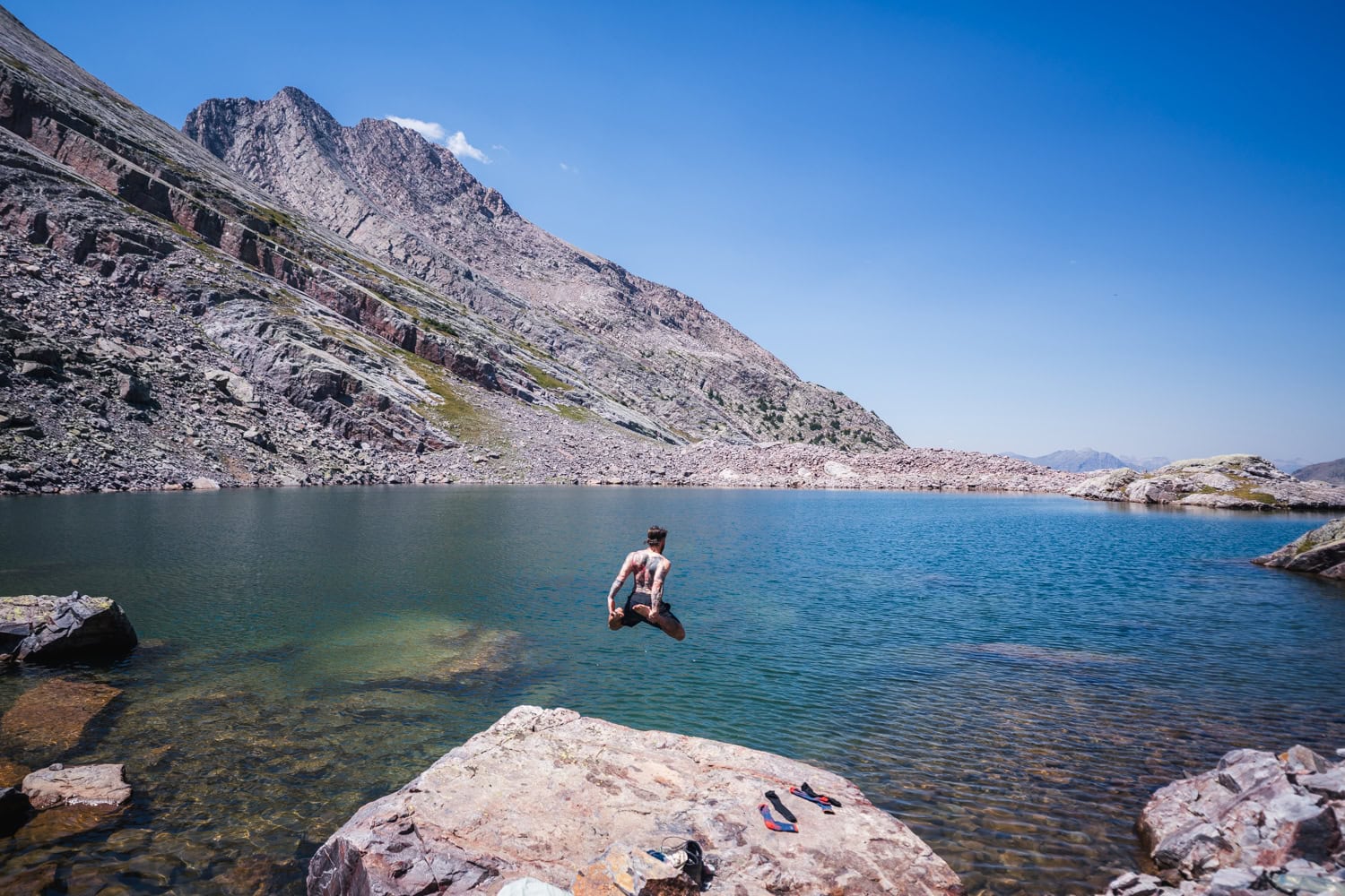 Sean Oblizalo from vows and peaks jumping into an alpine lake.