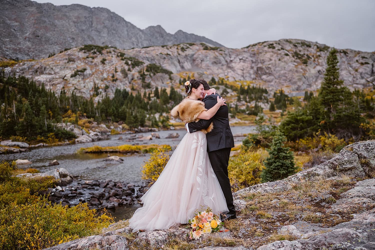 Bride and groom hugging near an alpine lake after sharing their vows at their Colorado elopement.